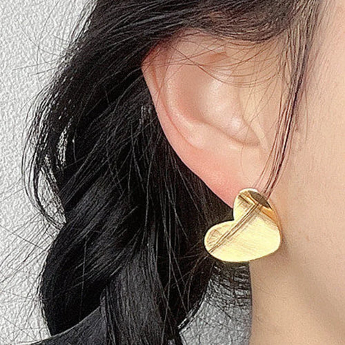 Gold brushed heart stud earring worn on the ear