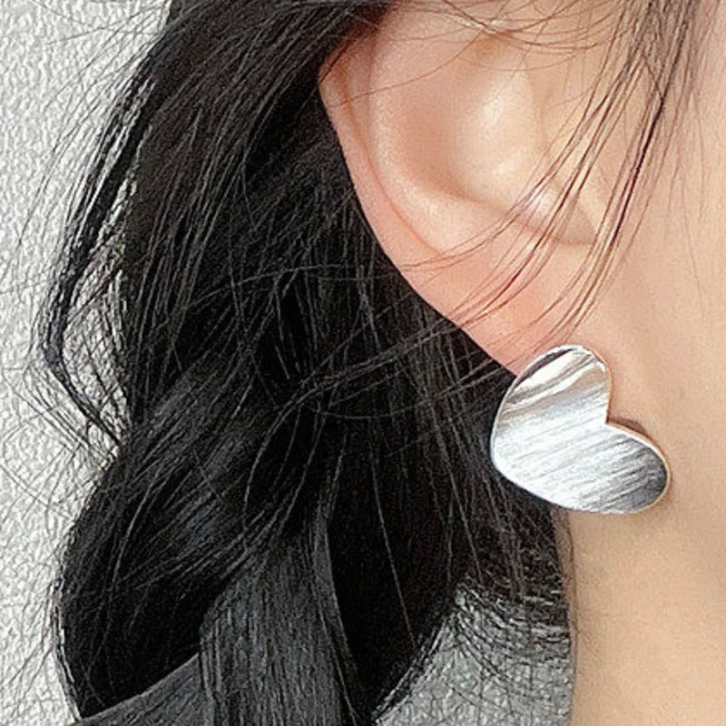 Silver brushed heart stud earring worn on the ear