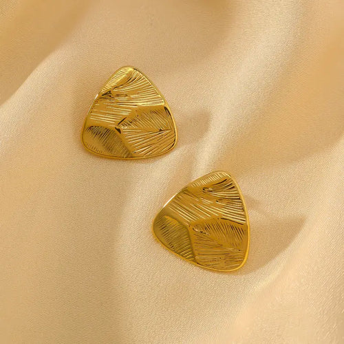 Gold brushed triangle stud earrings on cream satin