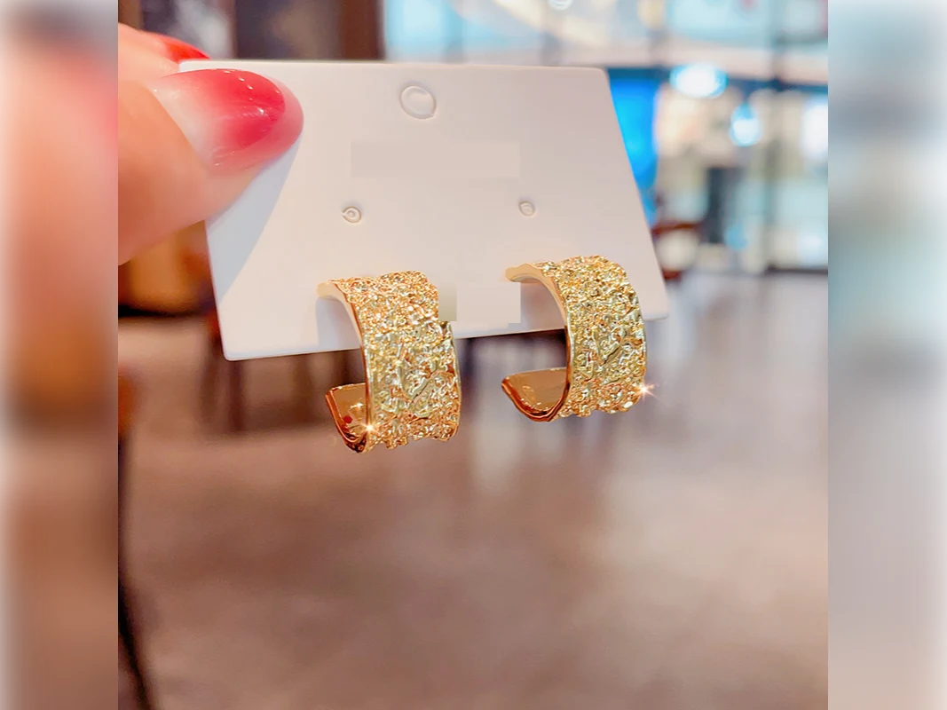 Gold textured hoop earrings on a display card