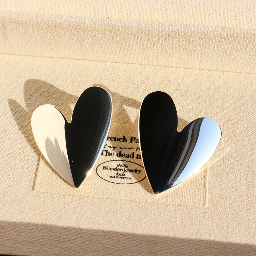Silver heart stud earrings on a linen jewellery box in sunlight