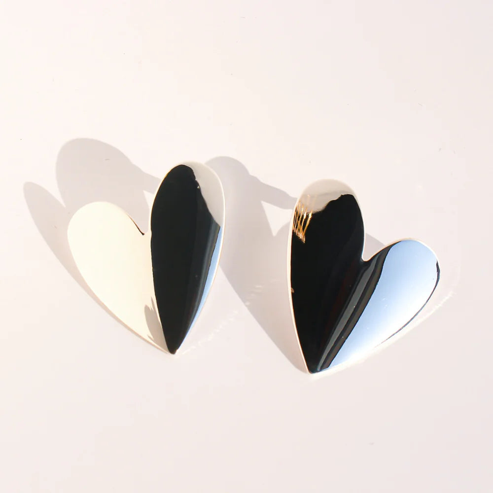 Pair of polished silver heart stud earrings on a white background
