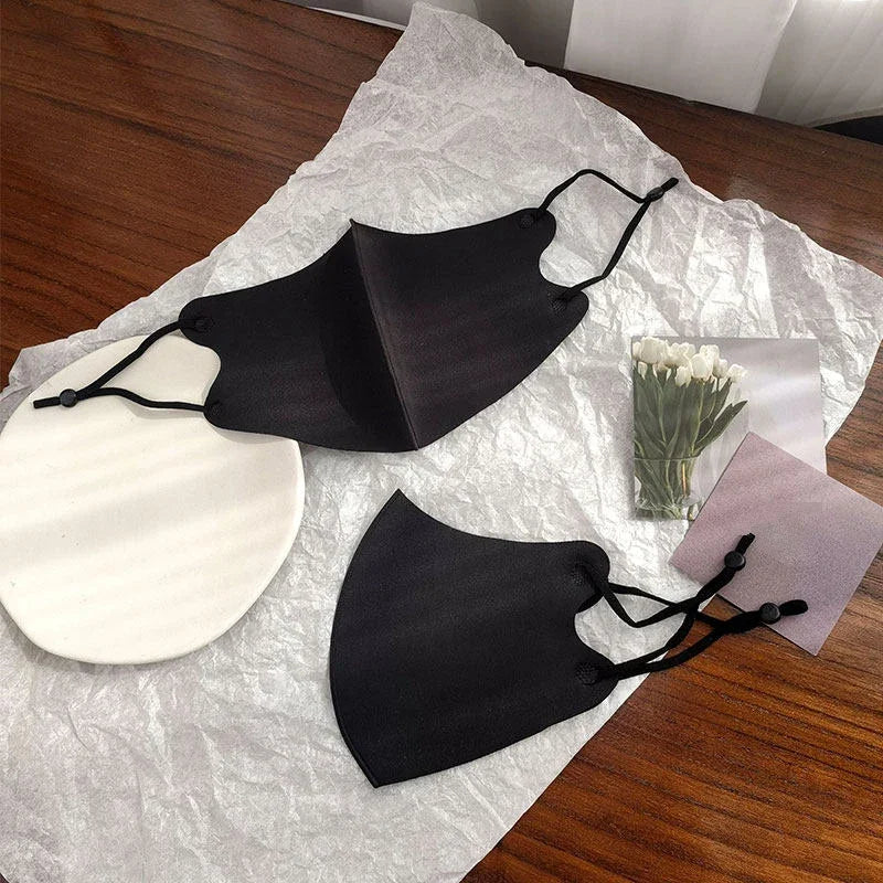 Two black washable face masks, one open showing the 3D shape