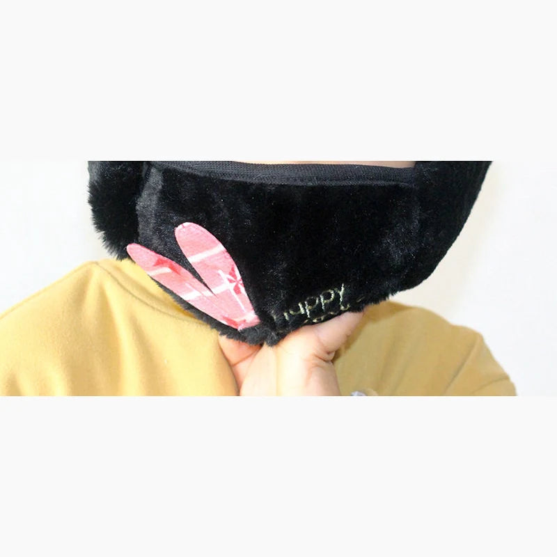 Child wearing black plush earmuffs with face mask and pink bunny ear patch