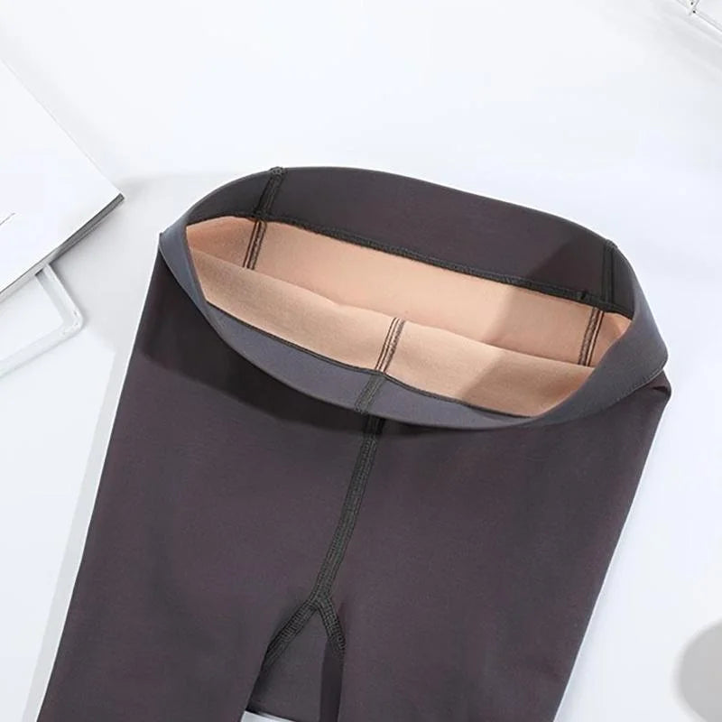Waistband of dark gray tights folded open to show the apricot skin-tone lining inside
