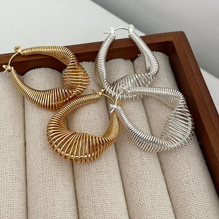 Spiral coil hoop earrings in gold and silver on a linen jewellery tray