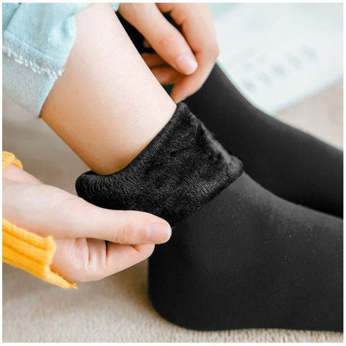 Hand folding down the cuff of a black velvet thermal sock to show the thick fleece lining